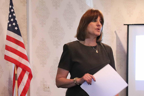 woman giving seminar with american flag in background
